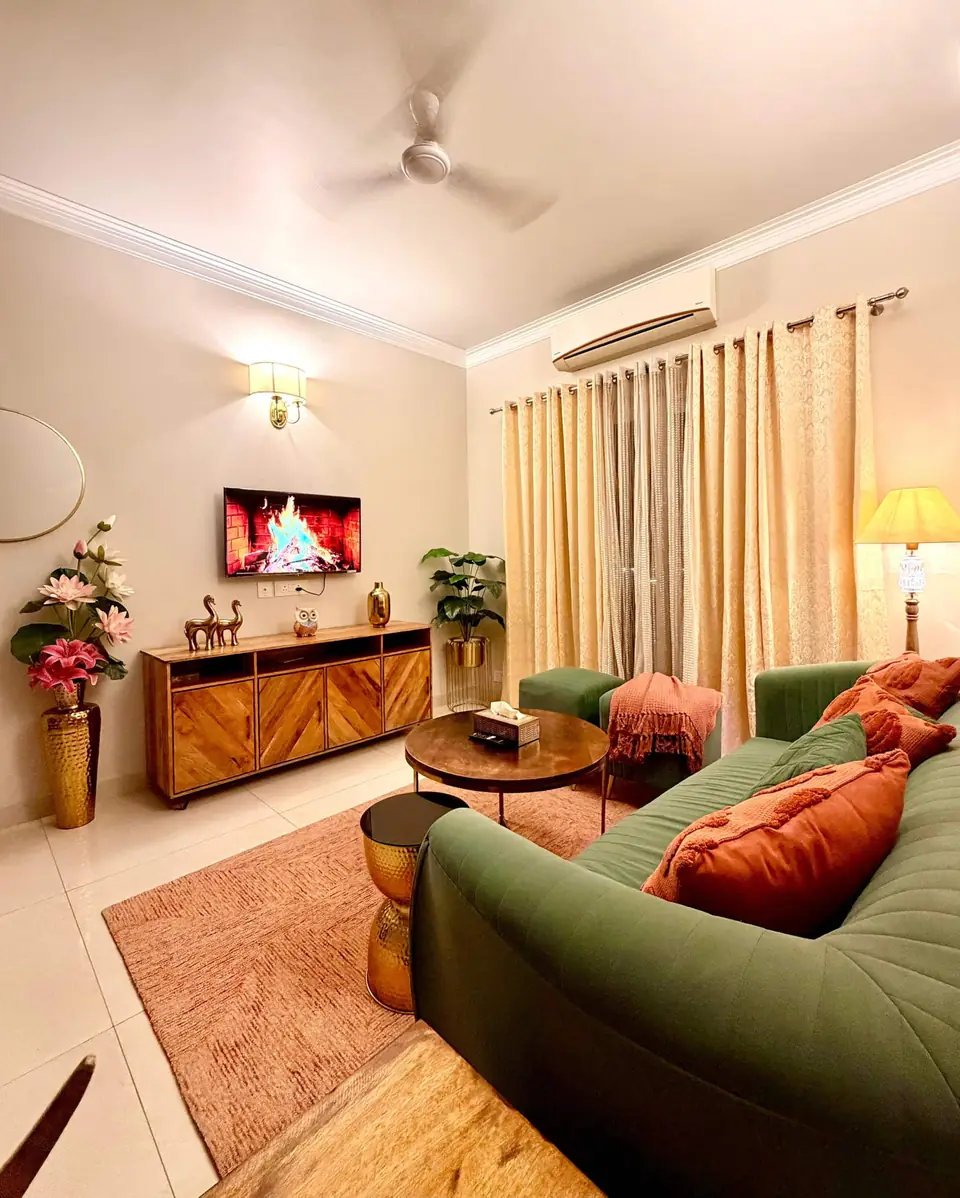 Living room with green sofa, TV unit and tall curtains